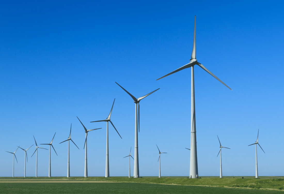 A line of wind turbines with blue sky above them.